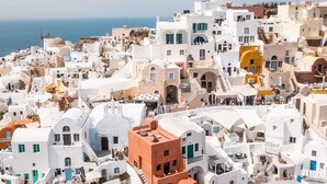 A coastal town with white buildings and a prominent orange structure. - Terracotta Cave House (1) (Santorini)
