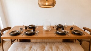 A dining table set with plates, glasses, and cutlery, a vase, and a bench.