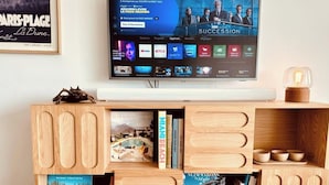 A flat-screen TV mounted on a wooden shelf with books and decorative items.
