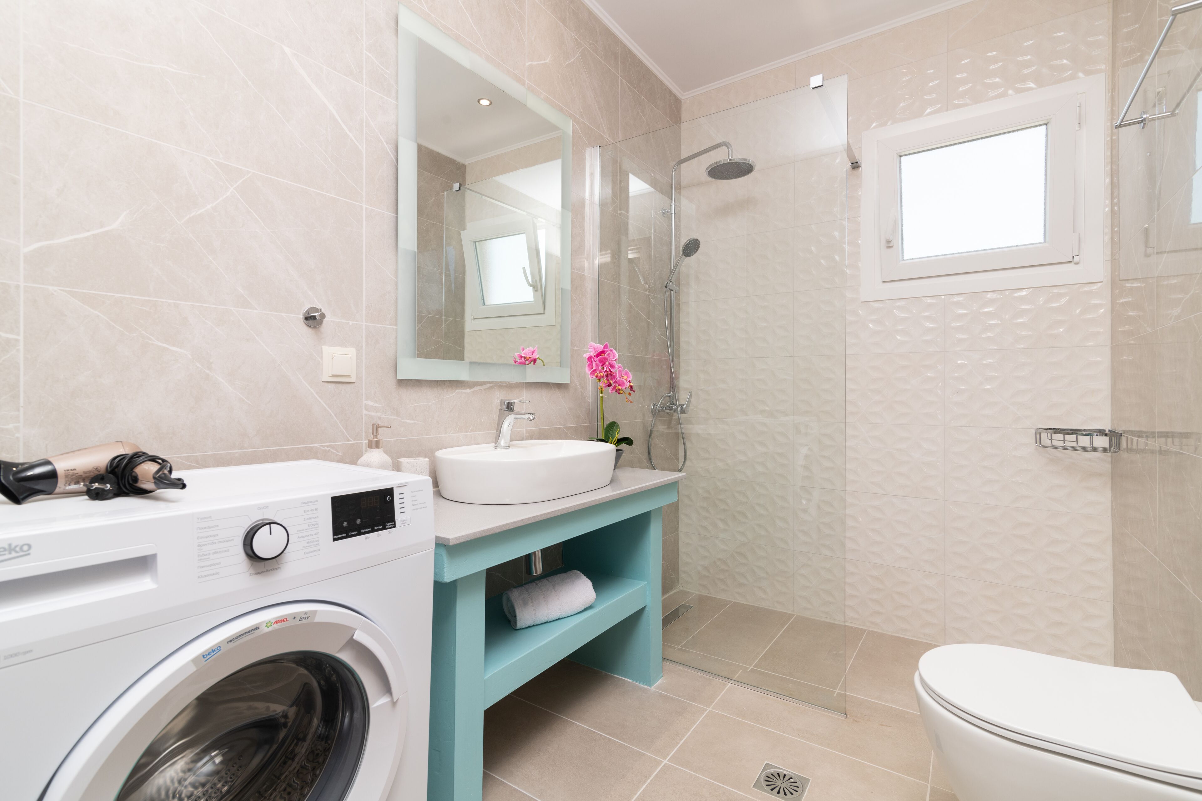A modern bathroom with a washing machine, sink, and toilet.