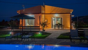 Une maison moderne dotée d’une piscine, d’un espace salon extérieur et d’une terrasse bien éclairée.