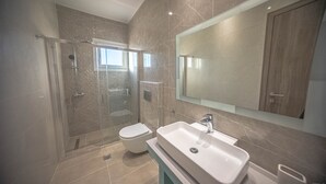 Une salle de bain moderne avec une douche à parois de verre, des toilettes et un grand lavabo.