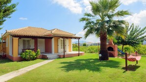 A house with a tiled roof, a front porch, and a palm tree.