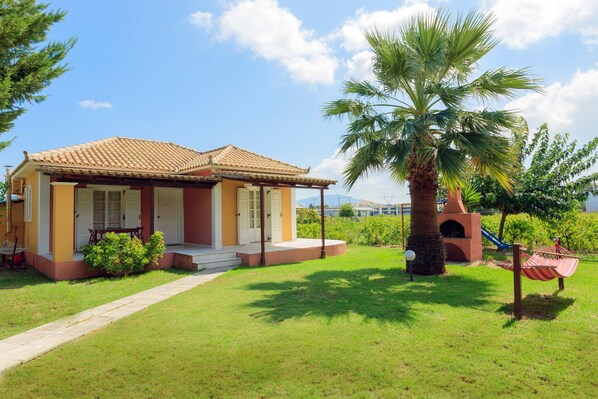 A house with a tiled roof, a front porch, and a palm tree.
