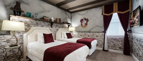 A hotel room with two beds, a stone wall, a ceiling with exposed beams, a fireplace, and a window with curtains.