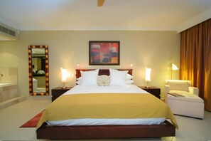 A hotel room with a large bed, two bedside tables, a mirror, a painting, and a chair.