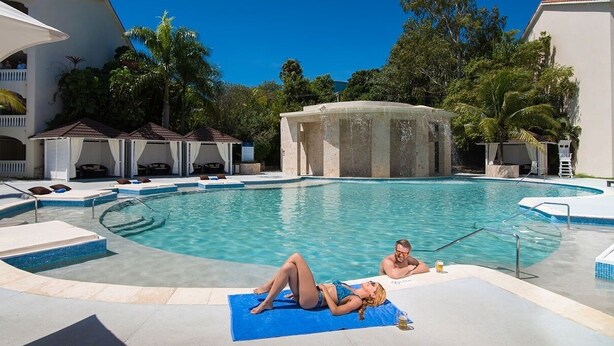 A swimming pool with lounge chairs and a hot tub.