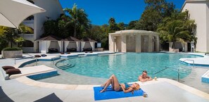 A swimming pool with lounge chairs and a hot tub. - Luxurious 1 Bedroom Presidential Suite (Puerto Plata)
