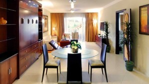 A modern dining area with a glass table, four chairs, and a central vase.