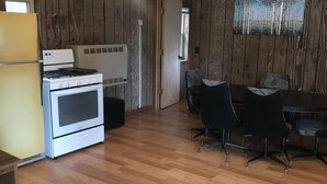 A kitchen with a stove, refrigerator, and dining table with chairs.