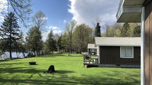A grassy yard with a wooden cabin, a barbecue grill, and a picnic table.