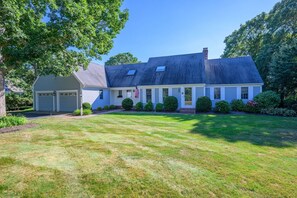 Une maison à deux étages avec un garage, une véranda et une pelouse bien entretenue.