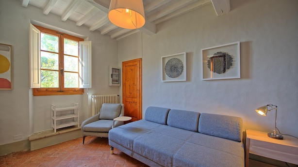 A cozy room with a blue sofa, a wooden door, and a window with shutters. - Inviting 6-bed House in Brindisi (Brindisi)