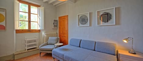 A cozy room with a blue sofa, a wooden door, and a window with shutters.