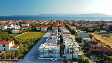 A coastal residential area with a mix of modern and traditional buildings, a main road, and a view of the sea.