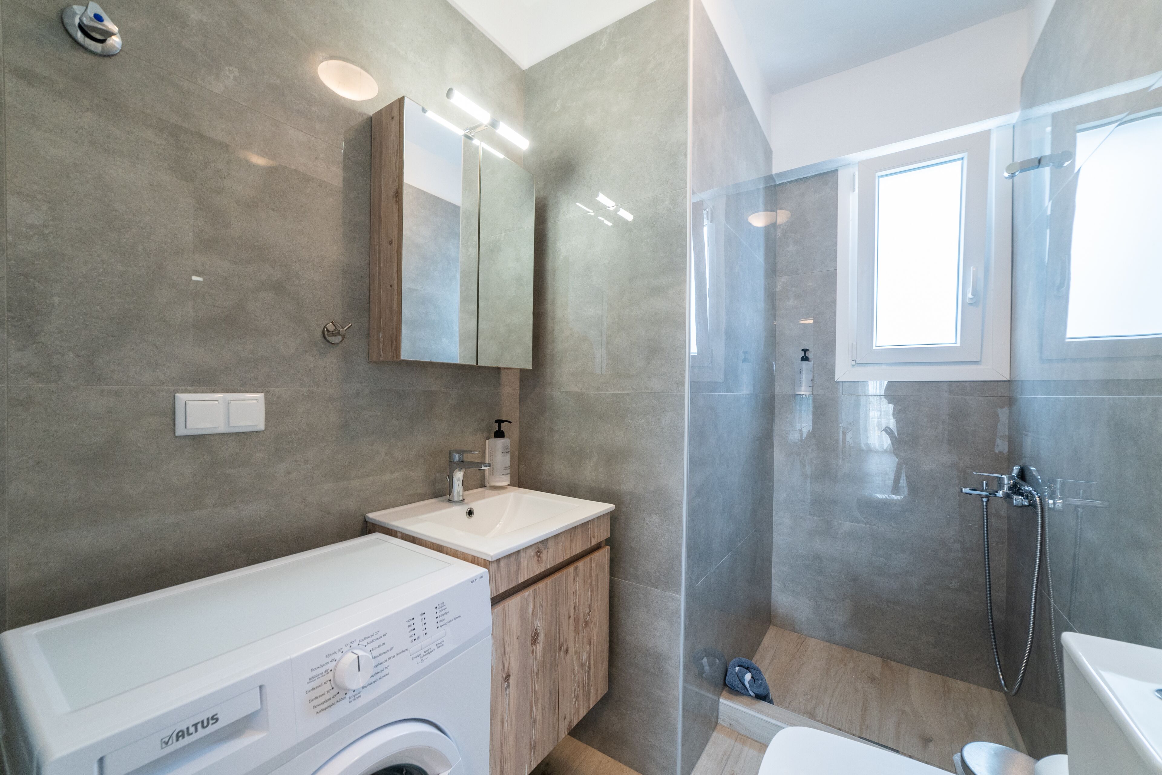 A modern bathroom with a washing machine, a sink, and a shower area.