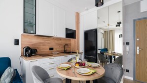 Une cuisine moderne avec des meubles blancs, un plan de travail en bois et un coin repas doté de chaises à revêtement gris.