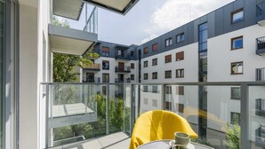Un appartement moderne doté d’un balcon, de grandes fenêtres et offrant une vue sur les immeubles voisins.