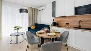 Une cuisine moderne avec des meubles blancs, un plan de travail en bois et un micro-ondes noir.