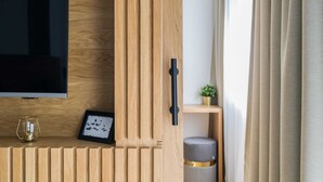 Un meuble en bois pour la télévision, sur lequel est posée une télévision à écran plat, ainsi qu’un tableau encadré et une petite plante.