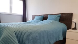 A bedroom with a bed, a nightstand, and a window.