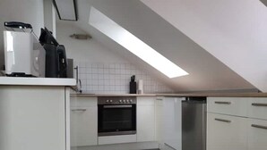 A modern kitchen with white cabinets, a stainless steel refrigerator, and a built-in oven.