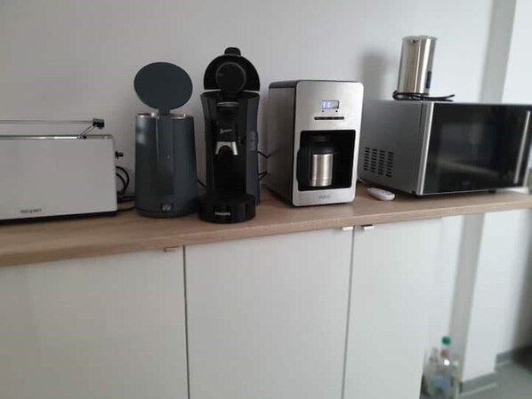 A kitchen counter with a toaster, a coffee maker, a water dispenser, and a microwave.