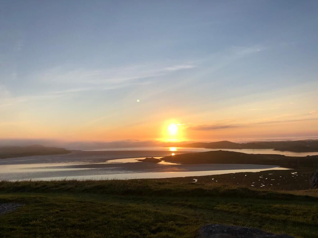 A sunset over a lake with distant hills.