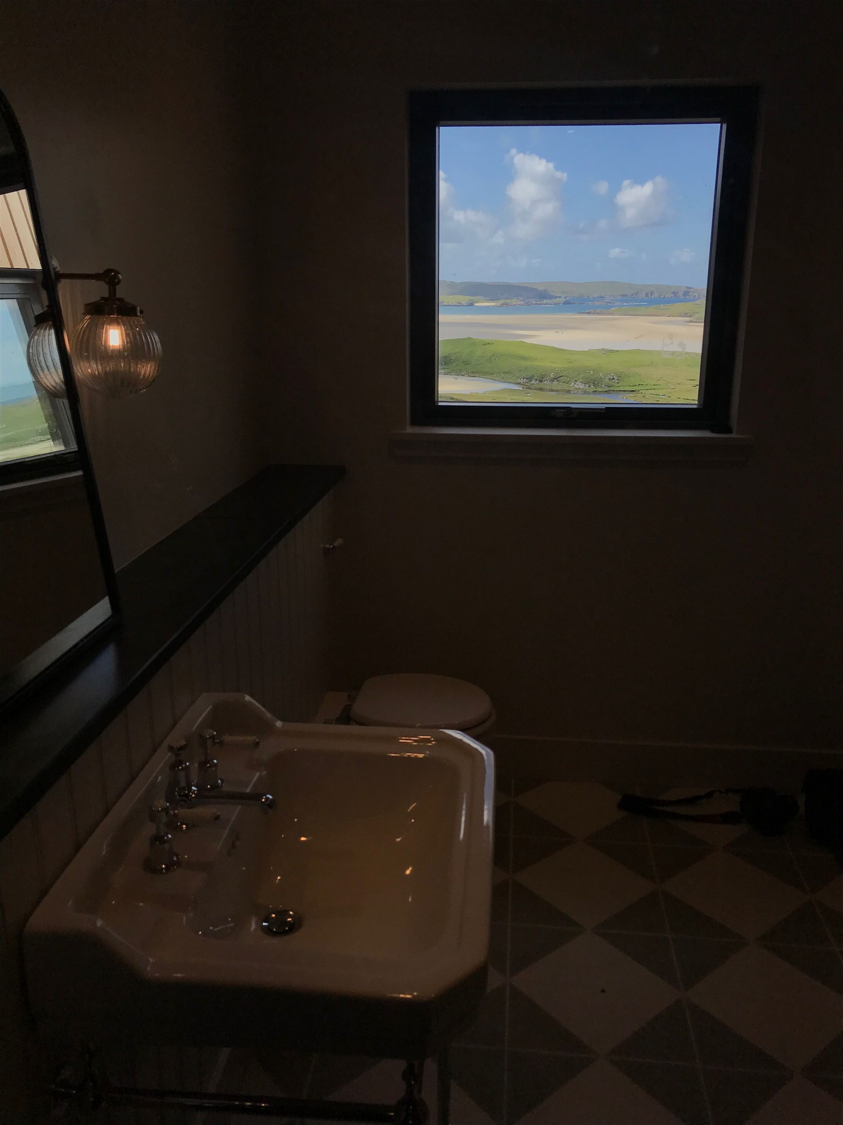 A bathroom with a window, a sink, and a toilet.