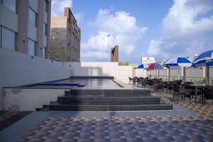 Uma área de terraço ao ar livre com piscina, mobili ário de jardim e vista para o horizonte da cidade.