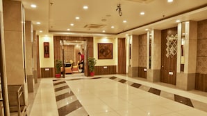 A spacious lobby with a polished tile floor, a reception desk, and potted plants.
