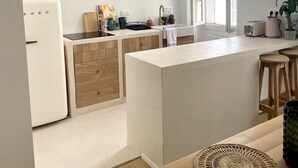 A modern kitchen with a central island, wooden cabinets, and a large window providing natural light.