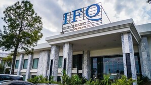 Ein Hotel mit auffälligem Schild mit der Aufschrift "IFQ HOTEL RESORT" und moderner Architektur, die Marmorsäulen und große Fenster umfasst.