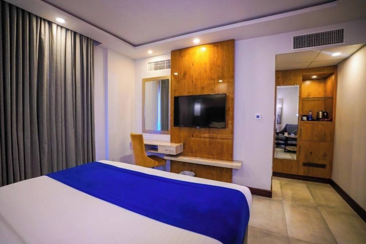 Ein Hotelzimmer mit Bett, Schreibtisch, Fernseher und Kleiderschrank.
