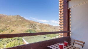 A balcony with a wooden bench and two red mugs, overlooking a mountainous landscape. - Les Lauzes D25 by Interhome (Les Menuires)