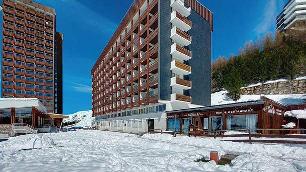A modern hotel with a multi-story structure, balconies, and a snow-covered ground. - Les Lauzes D25 by Interhome (Les Menuires)