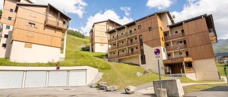 A multi-story residential building with a modern design, featuring balconies and a flat roof.