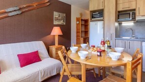 Een knus woongedeelte met een bank, eettafel en kitchenette.