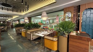 A modern restaurant with booth seating, pendant lighting, and decorative plants.