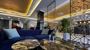 A modern lobby with a blue sofa, a marble coffee table, and a geometric decorative panel.