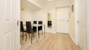 A dining area with a table and chairs, a mirror, and a door.