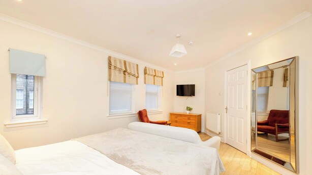 A bedroom with two beds, a dresser, a TV, and a large mirror.