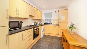 A compact kitchen with wooden cabinets, a microwave, stove, and a washing machine.