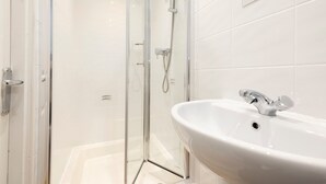 A modern bathroom with a glass-enclosed shower, a white sink, and a mirror above it. - Gorgeous Apartment near Edinburgh Castle (Edinburgh)