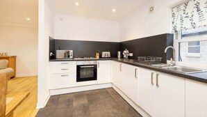 A modern kitchen with white cabinets, a black countertop, and a built-in oven. - Gorgeous Apartment near Edinburgh Castle (Edinburgh)