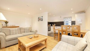 A modern living room with a sofa, a wooden coffee table, and a dining area with a table and chairs. - Gorgeous Apartment near Edinburgh Castle (Edinburgh)