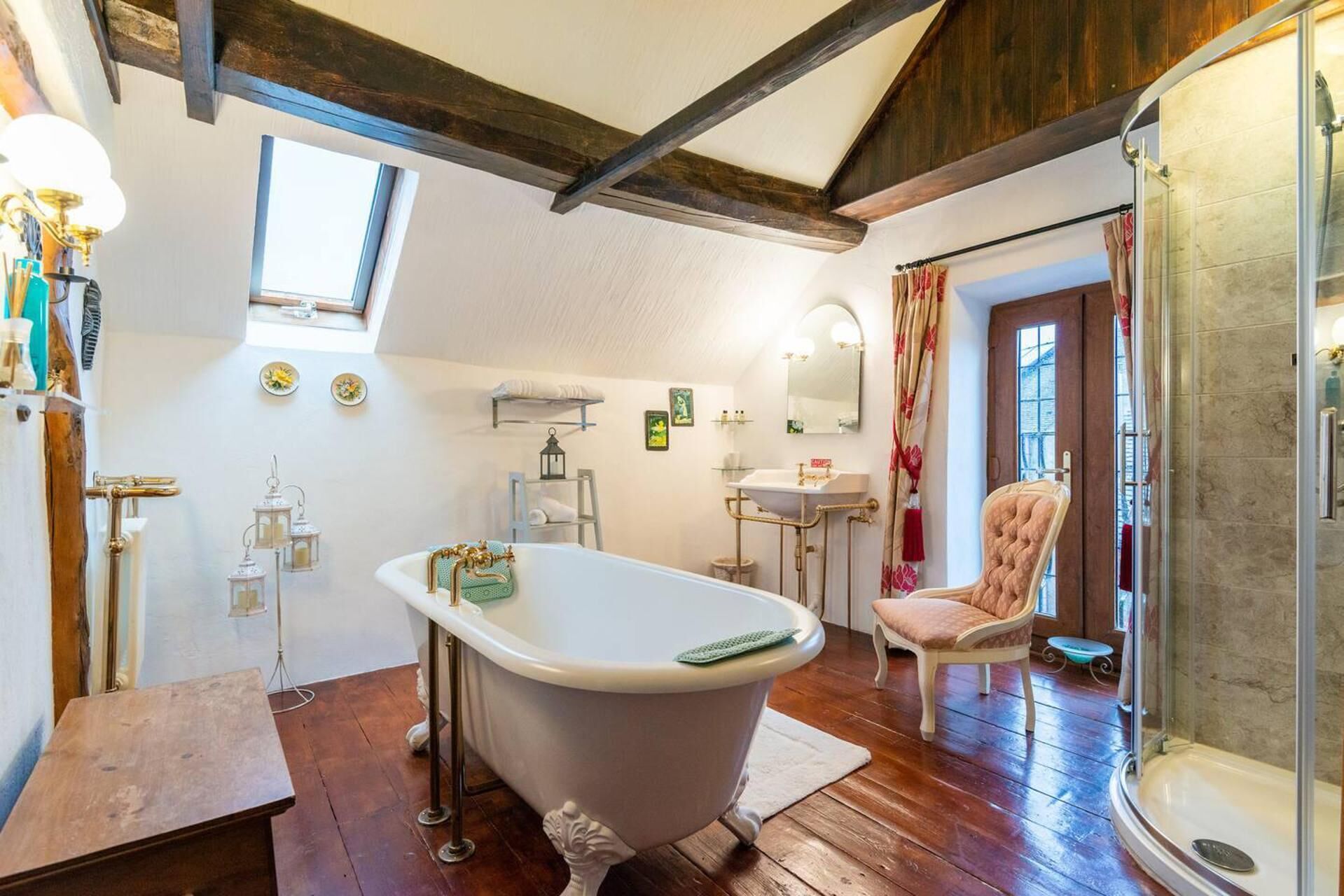 A bathroom with a freestanding bathtub, a vanity with a sink, a shower, and a chair.