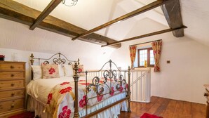 Ein Schlafzimmer mit einem hölzernen Bettgestell, einem Schminktisch, einem roten Teppich und einem Fenster mit Vorhängen.