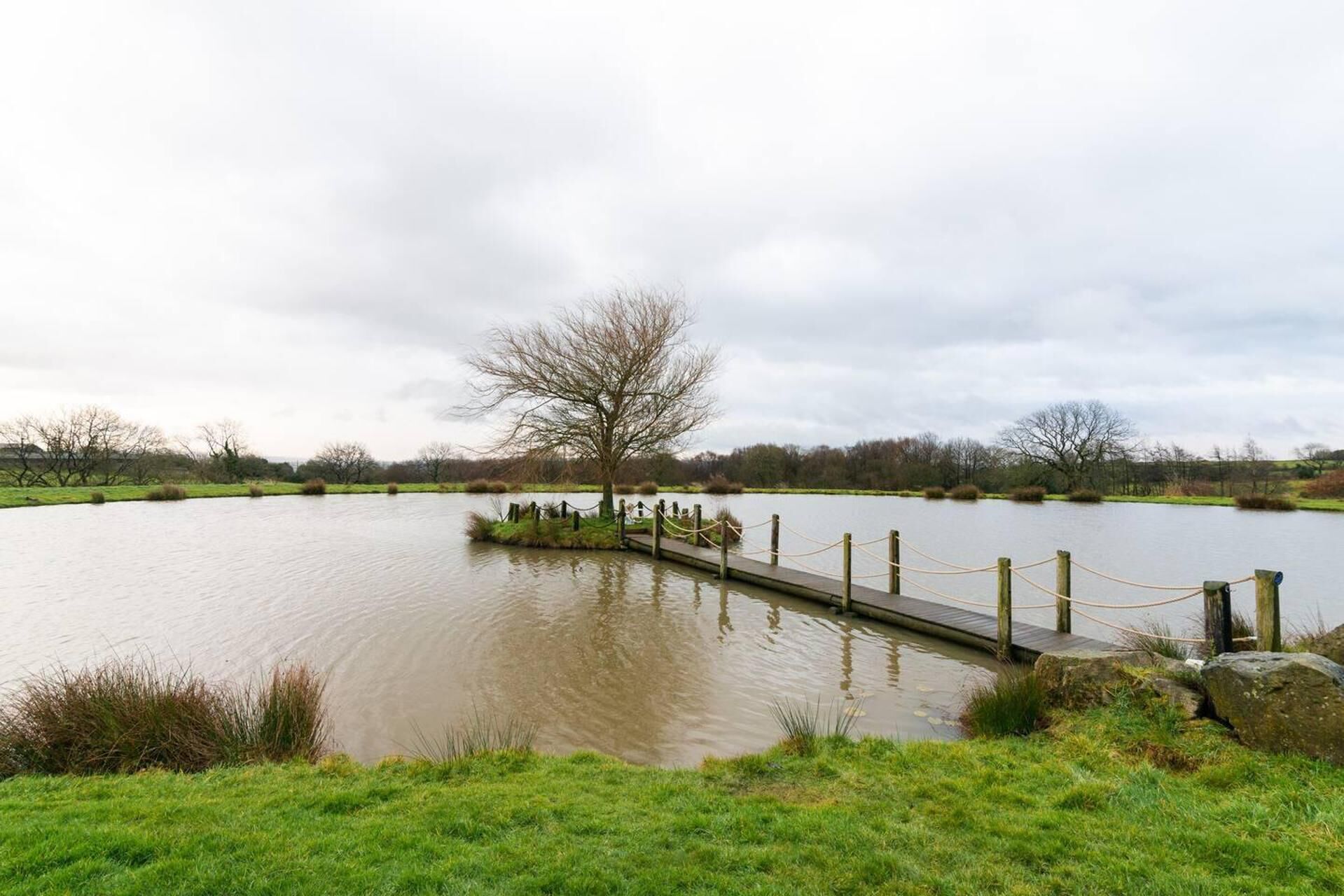 A calm lake with a wooden dock and a rope barrier.