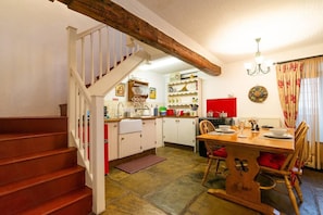 A kitchen with a wooden staircase, a dining table with chairs, and a red accent wall.